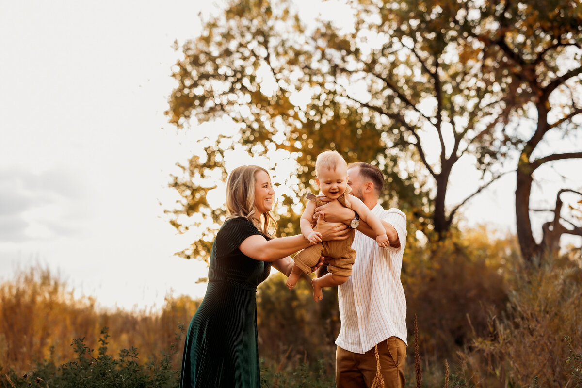 mom and dad swing infant son on a fall eventing