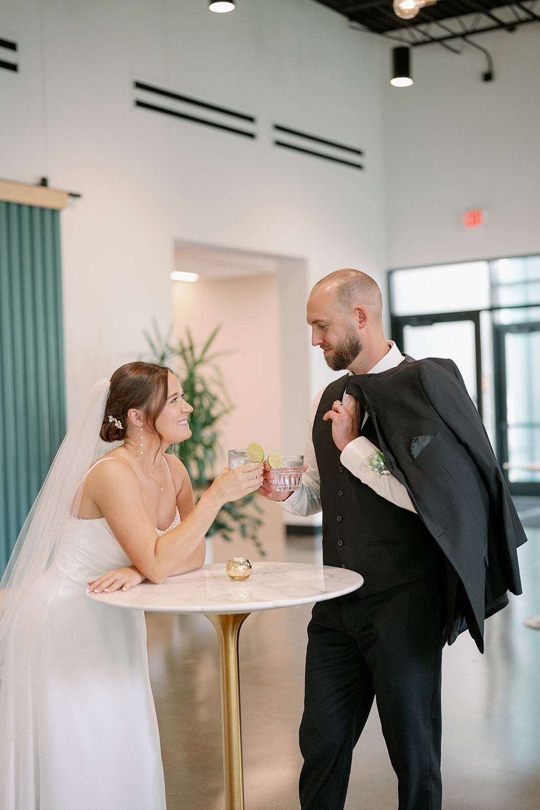 Bride and groom standing at a cocktail table sharing a drink during their elegant September wedding at Leona Road in Grand Rapids, Michigan.