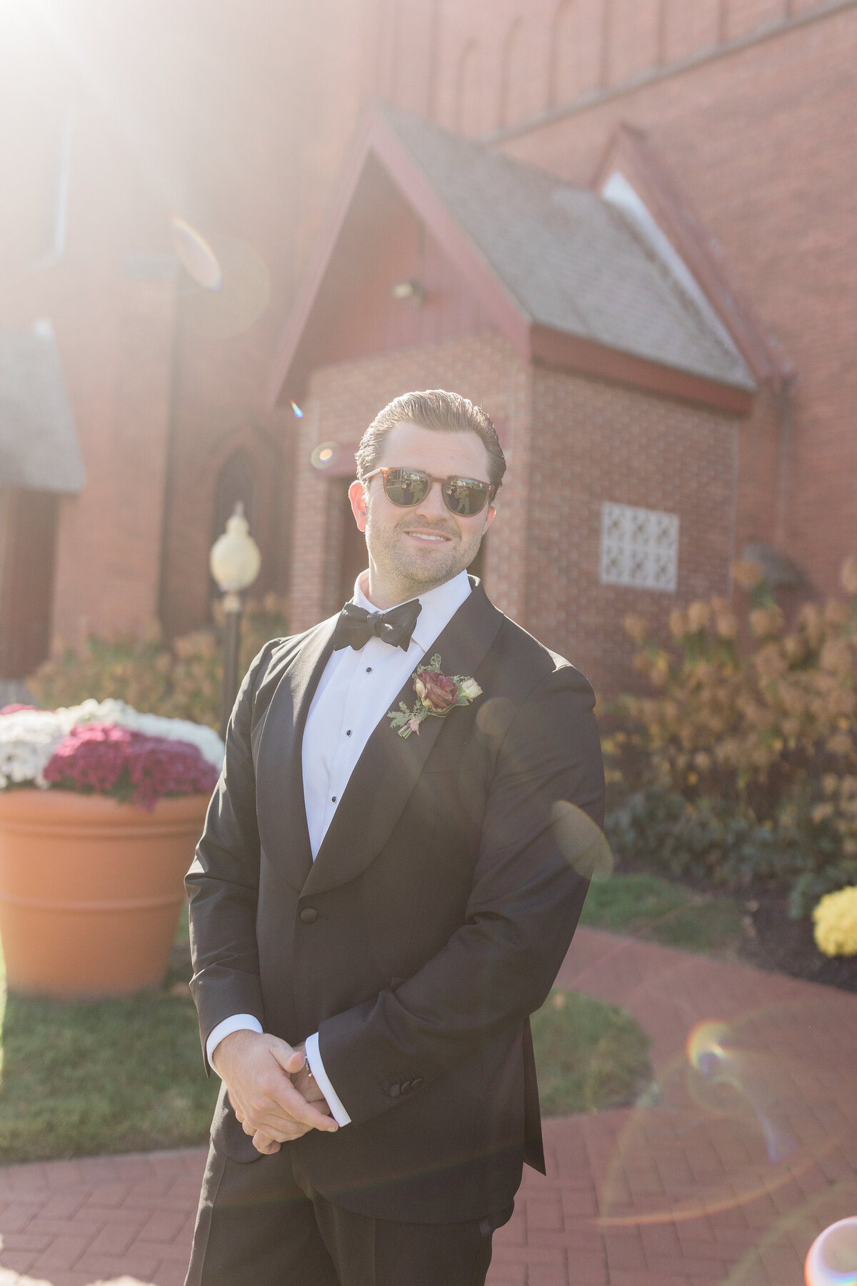 Groomsmen in sunglasses smiles before walking down the aisle 