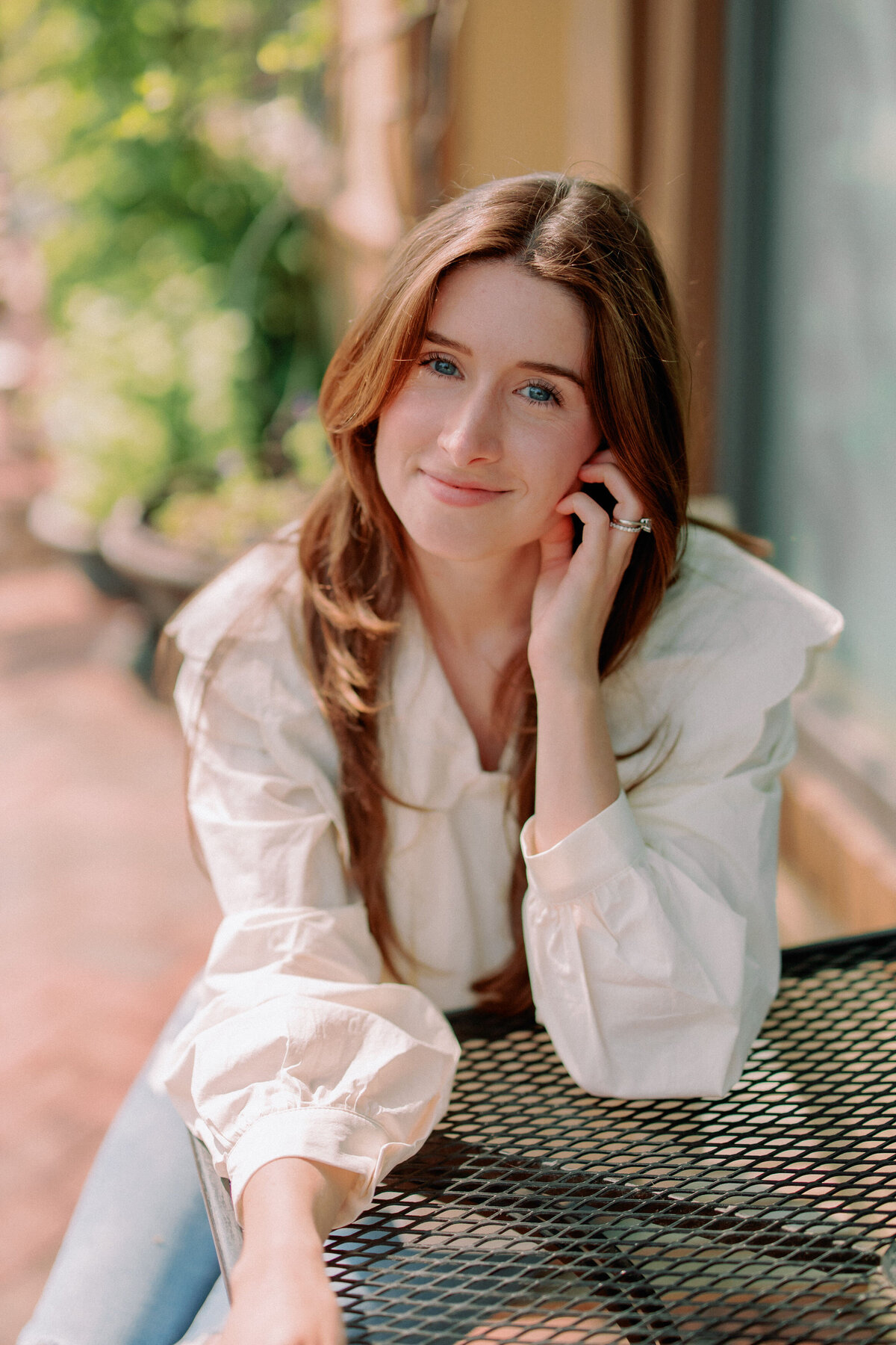 A person sitting at an outdoor table smiling with their elbow resting on the table