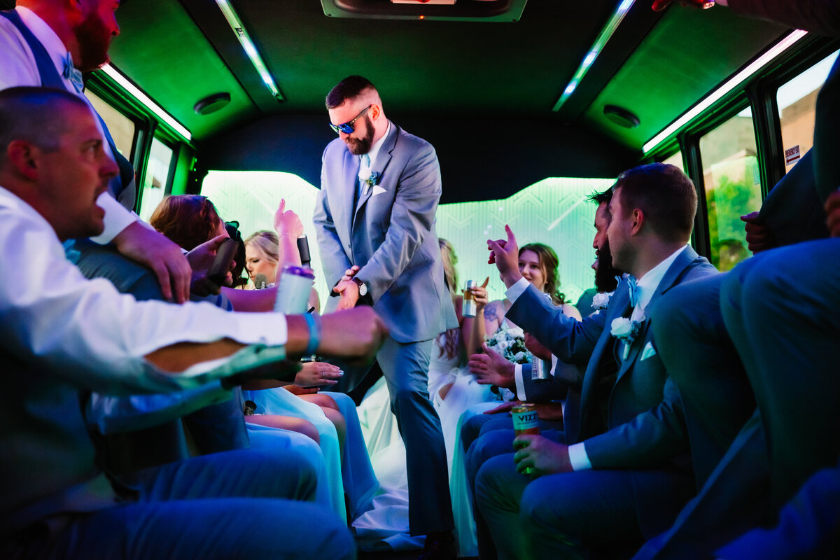 A wedding party drinks and celebrates inside a party bus
