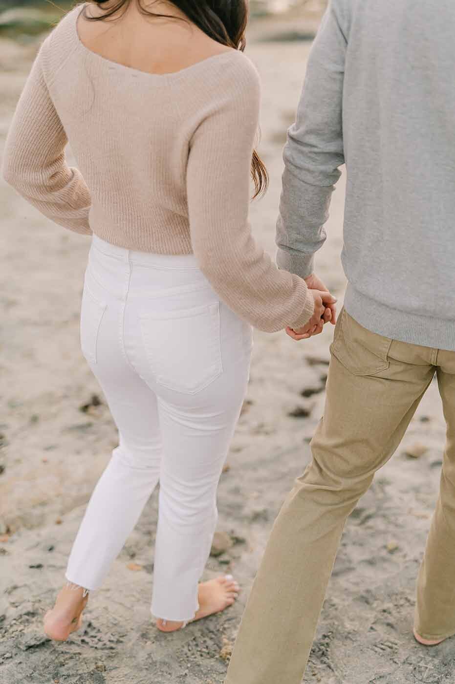 Couple holding hands on sandy beach New England