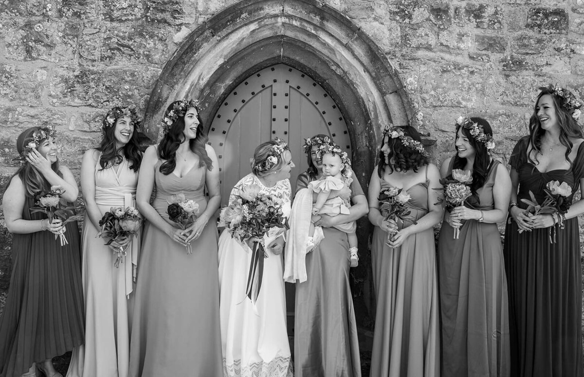 Bridal party all smile at each other infront of church