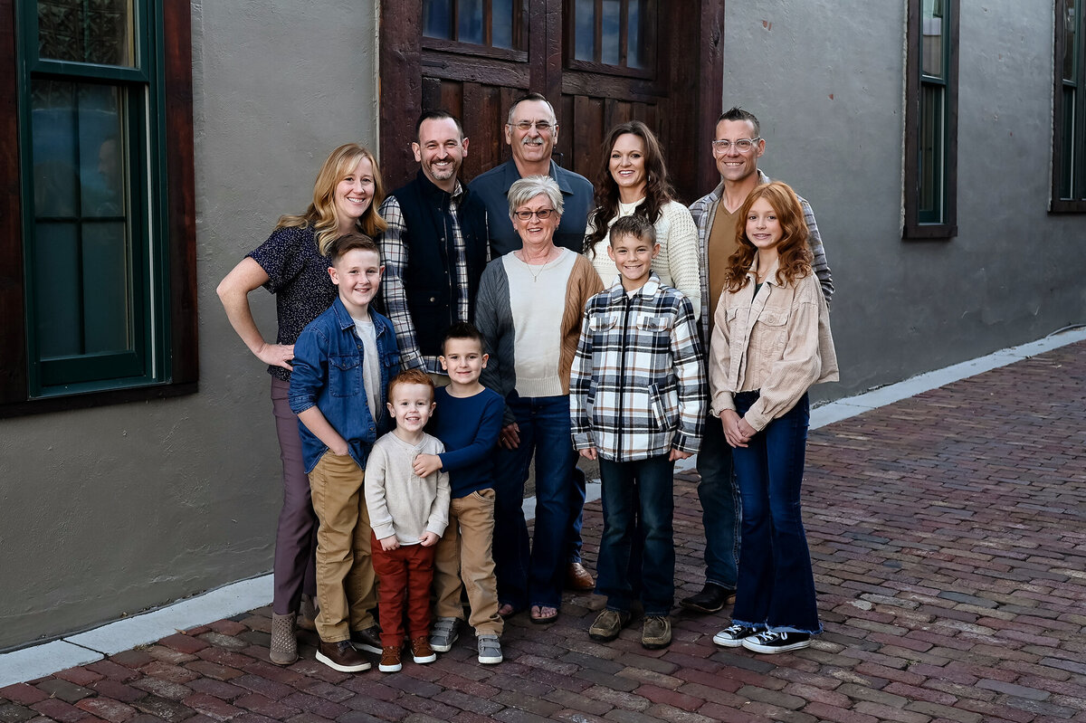 Adults and kids stand in an alley next to a wooden door for family portraits