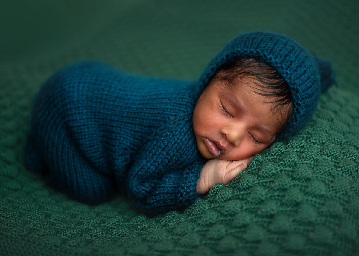 sleeping baby in blue onesie at newborn photoshoot