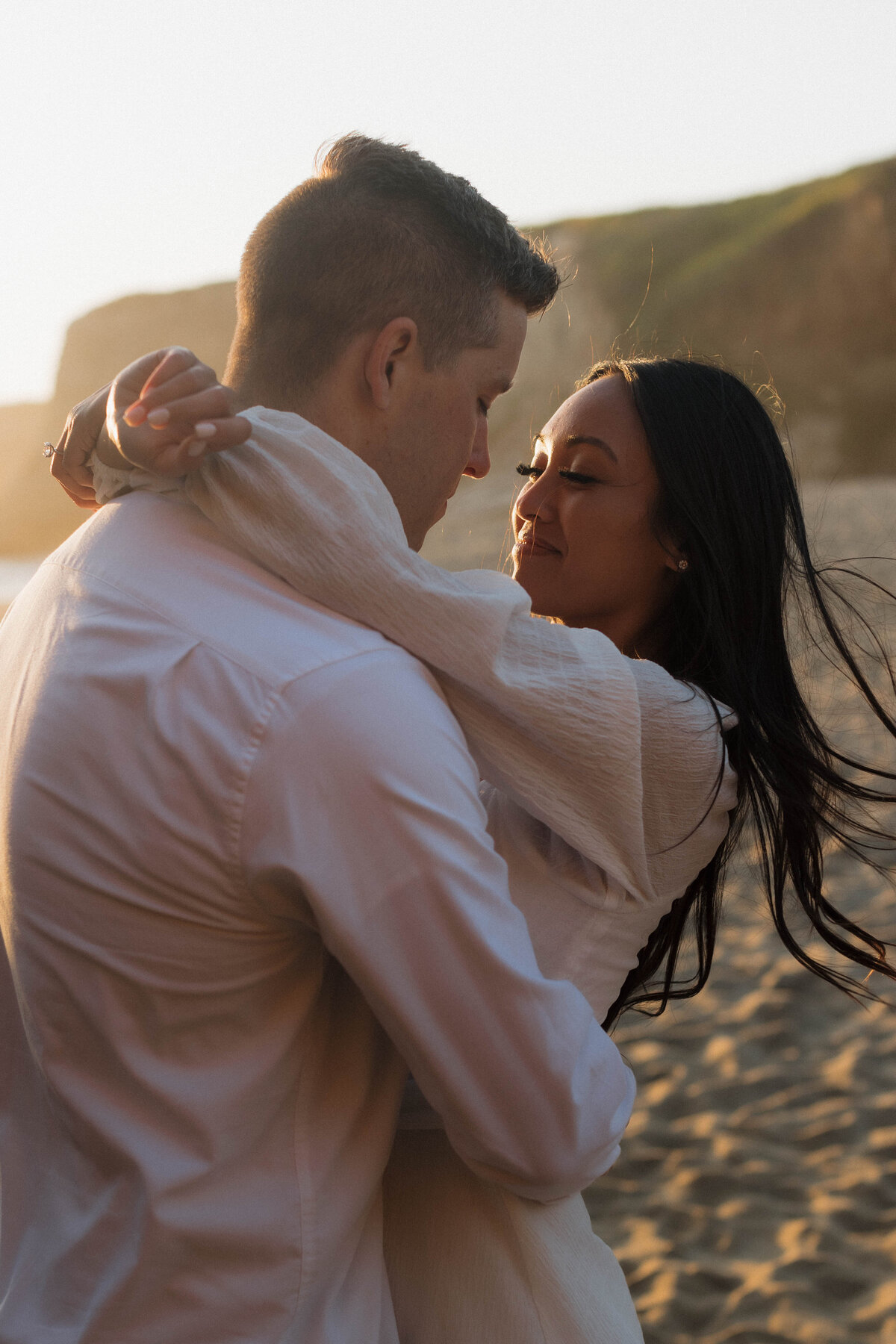 Couple walking along a sandy shore, captured in cinematic wedding photos that emphasize candid, emotional moments.