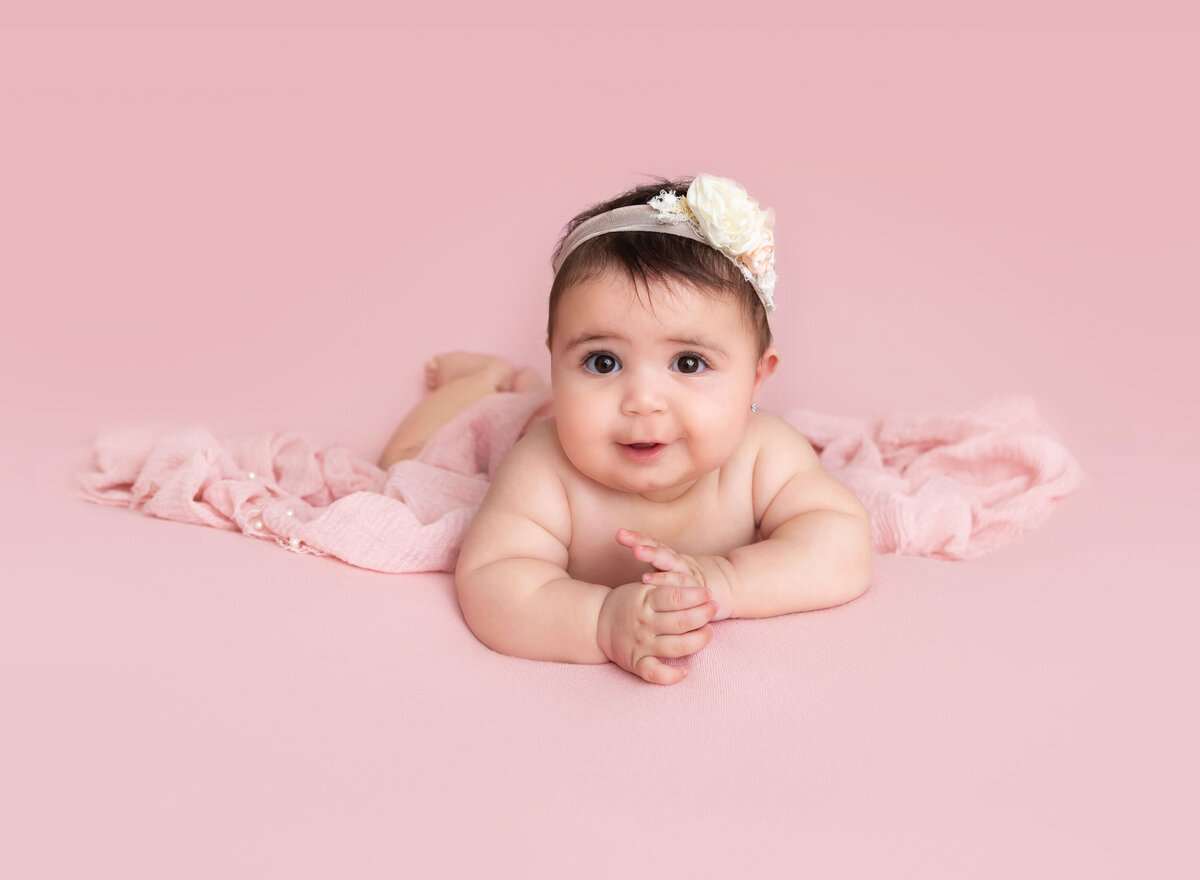baby girl on a pink blanket smiling during pictures taken at Brooklyn photo studio