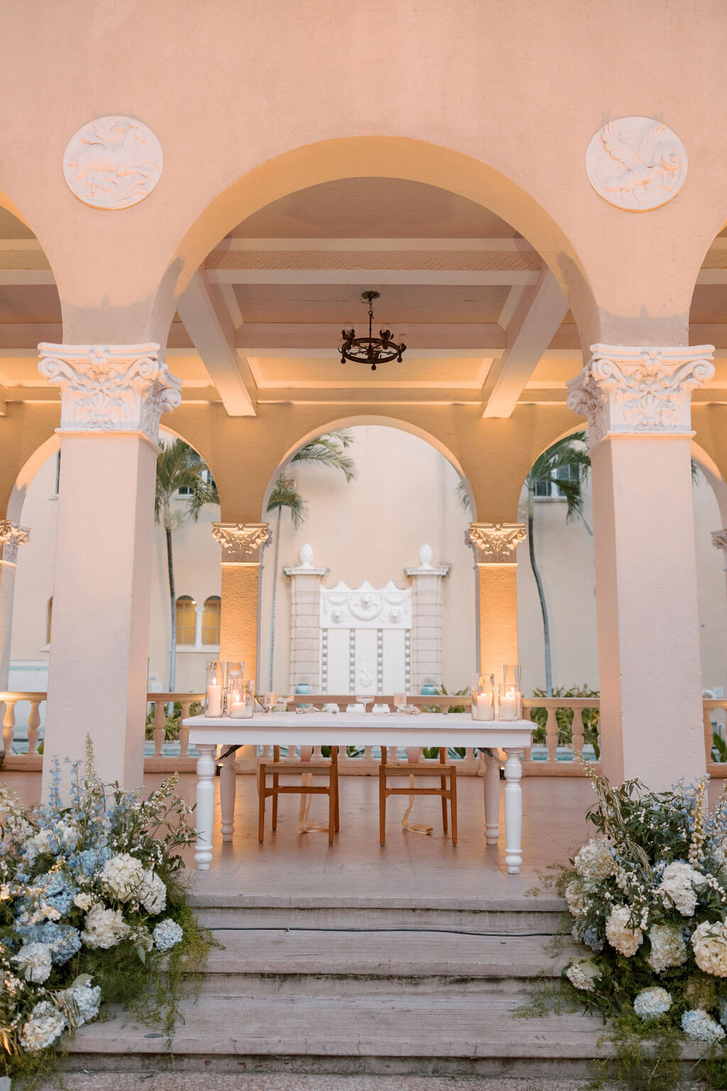 Sweetheart table with ground florals on each side under an arch