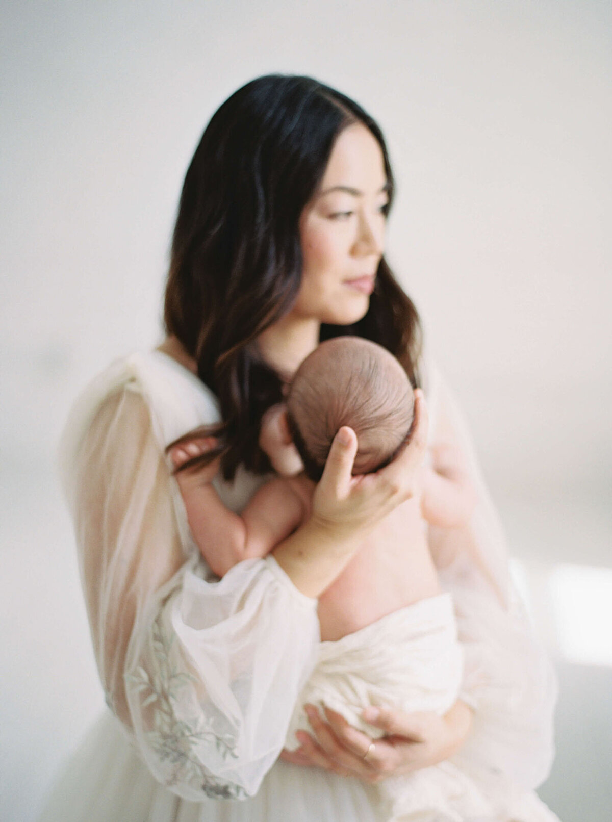 Mother holding newborn at studio with Bay Area newborn photographer session.