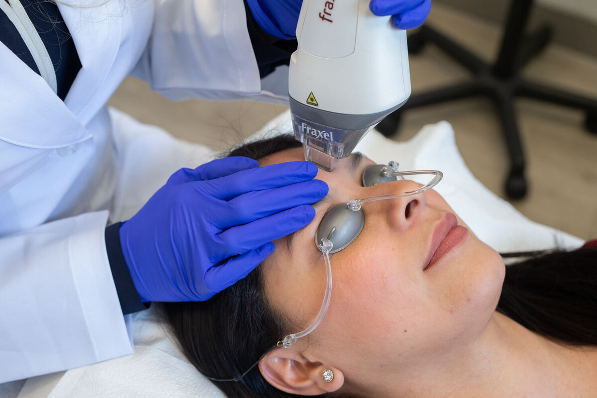 A woman is getting a laser treatment on her face.