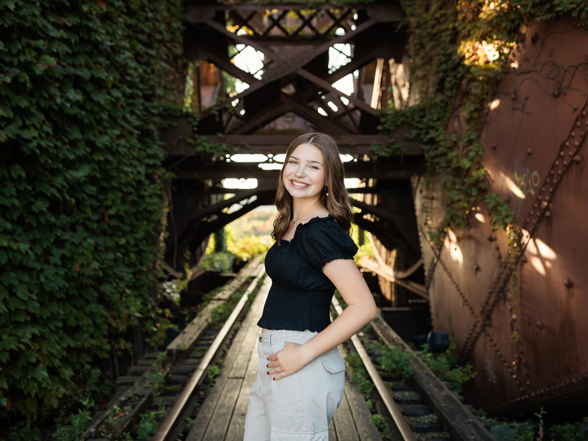 senior girl in black shirt posed at shooters on the water for senior portraits 