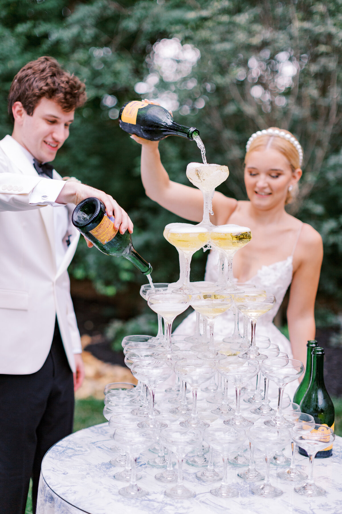 Couple pour champagne into a champagne tower for a toast