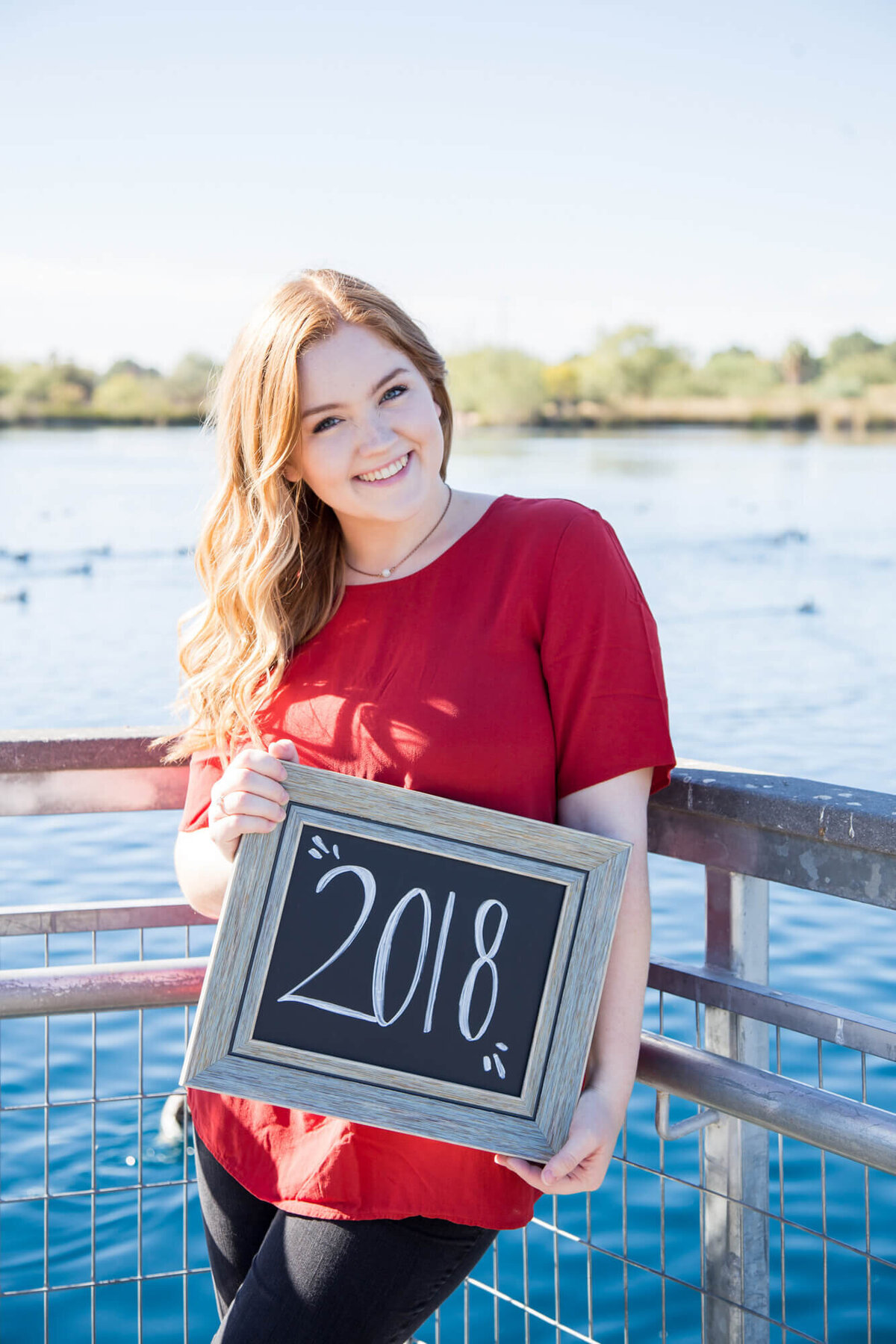 Happy Young woman holding a chalkboard sign in front of water