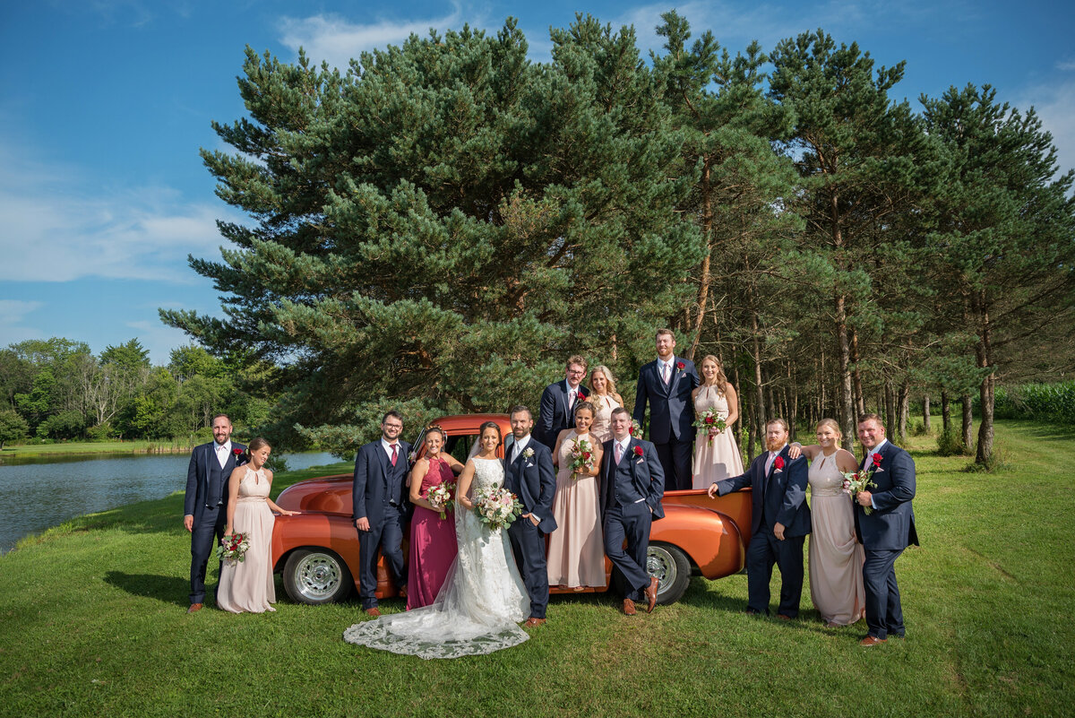 Wedding party posed by a vintage truck and pond.