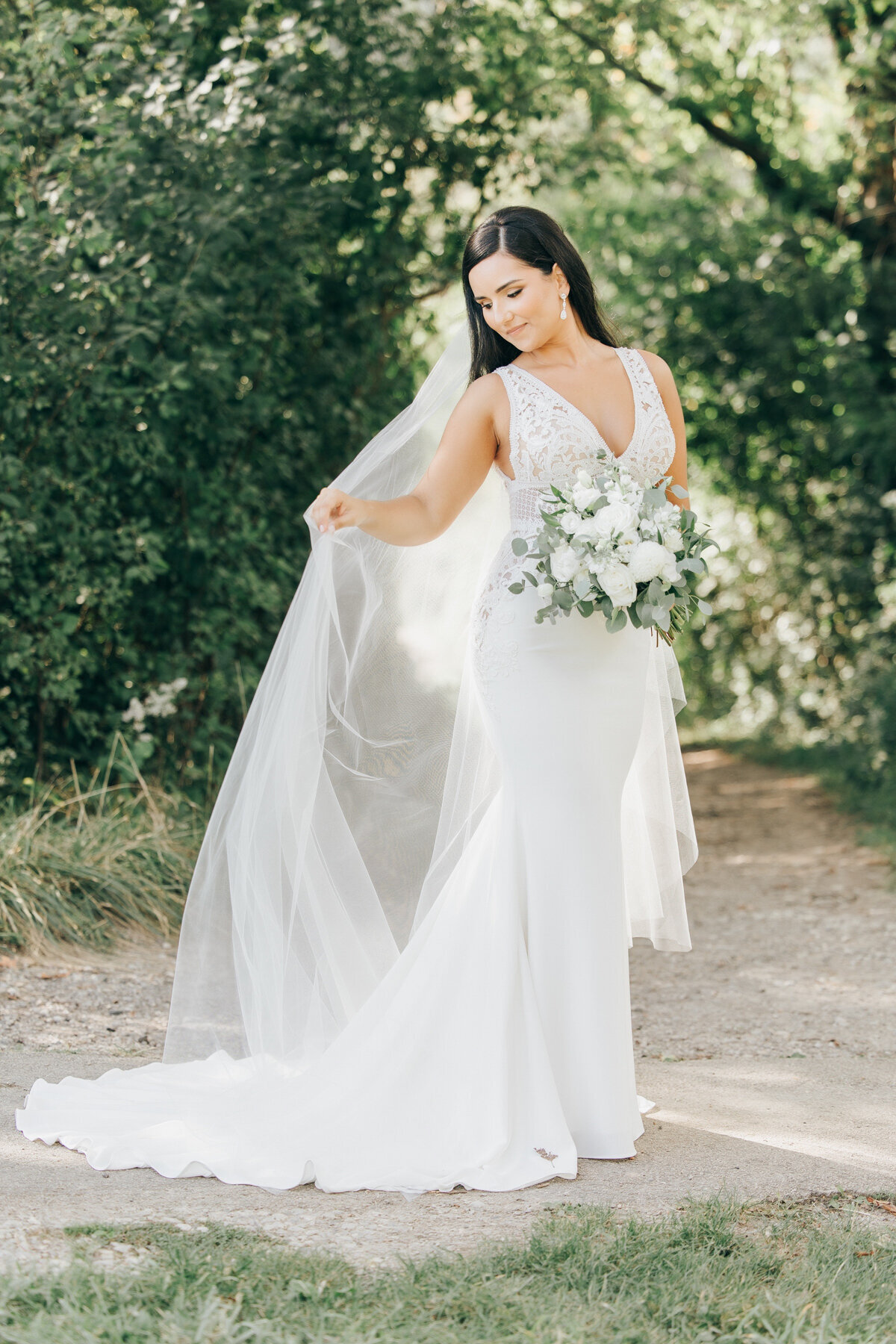 A bride wearing a beautiful white dress, long veil and holding a white wedding bouquet