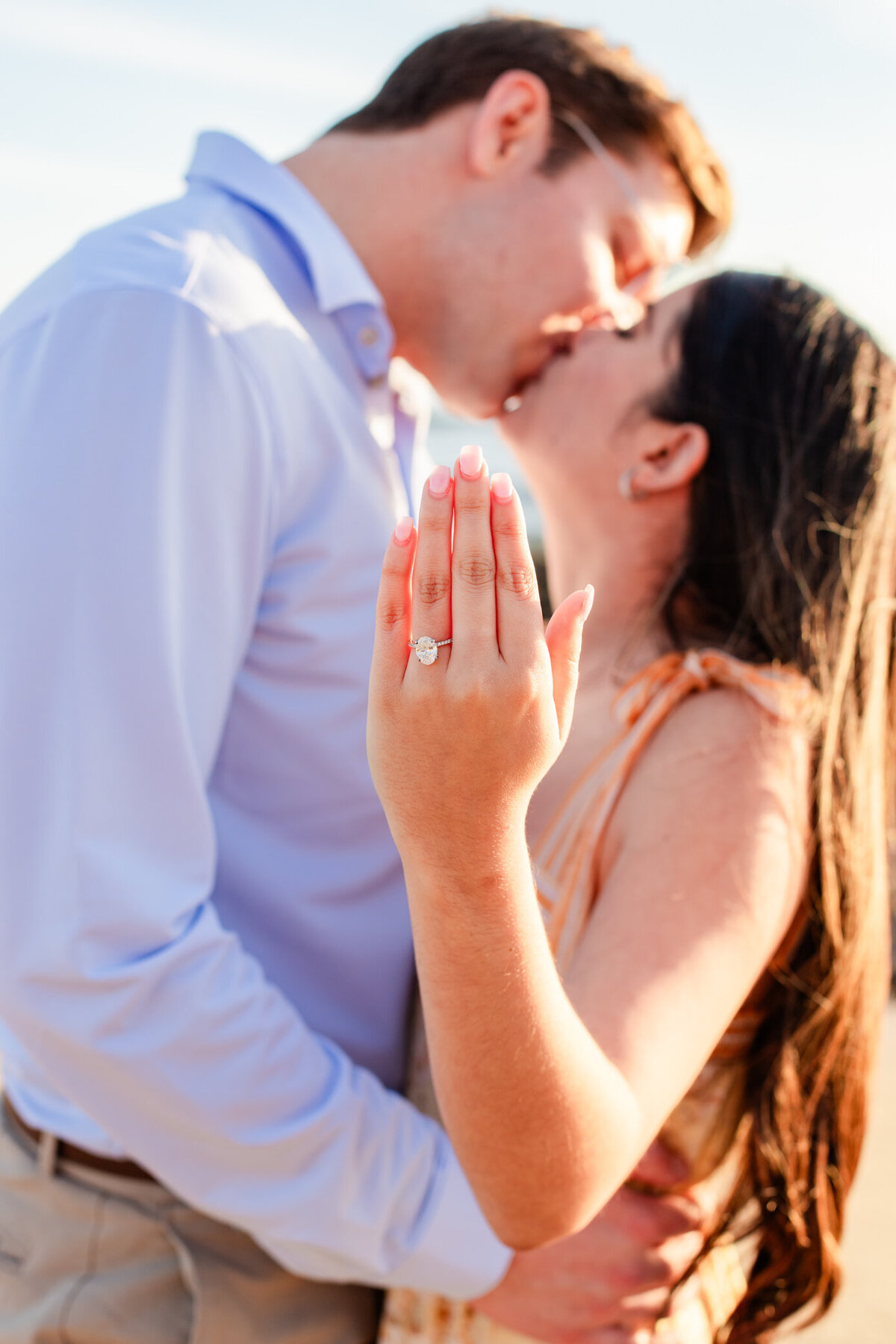 couple kiss and show off engagement ring