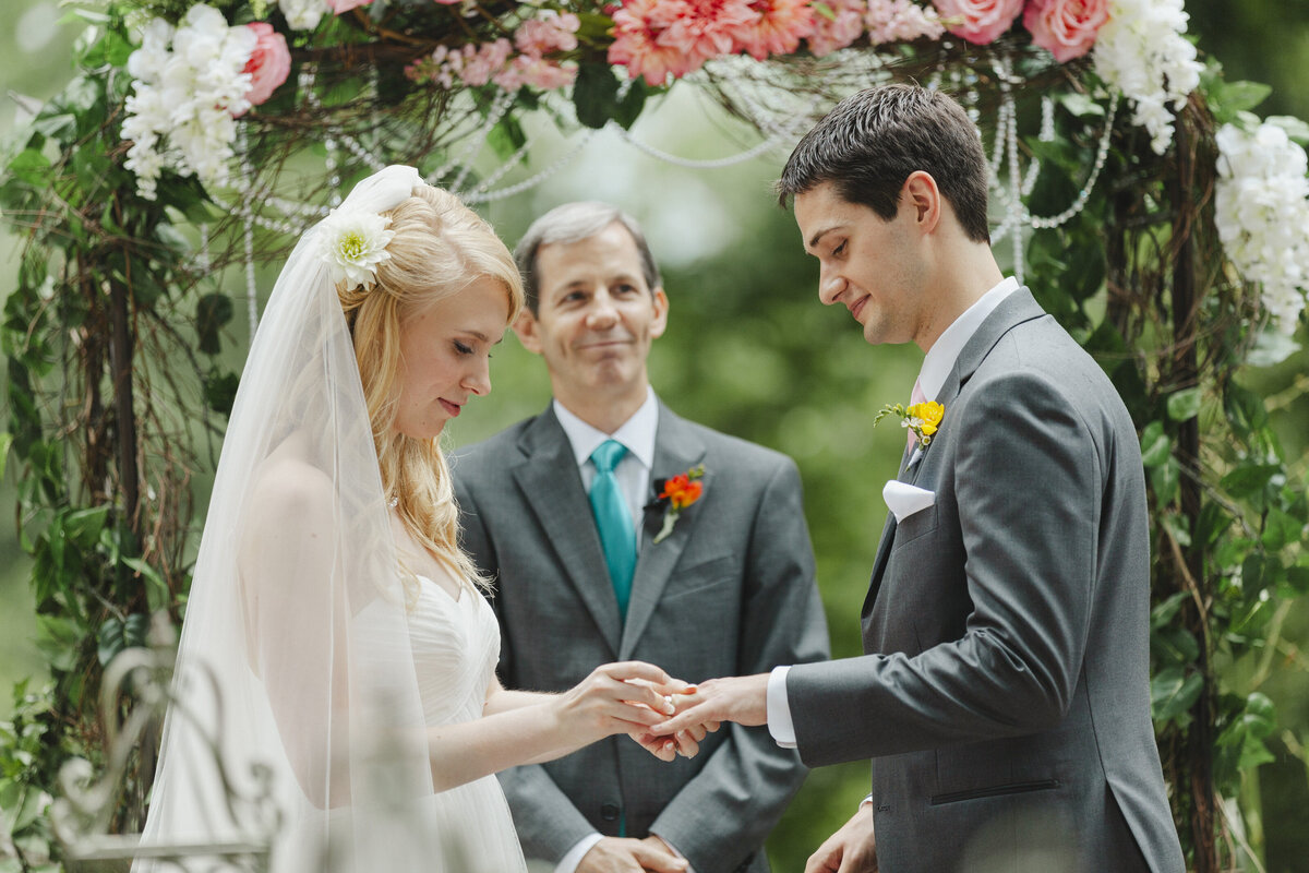 A person sliding a ring onto their partner's hand during their wedding ceremony 