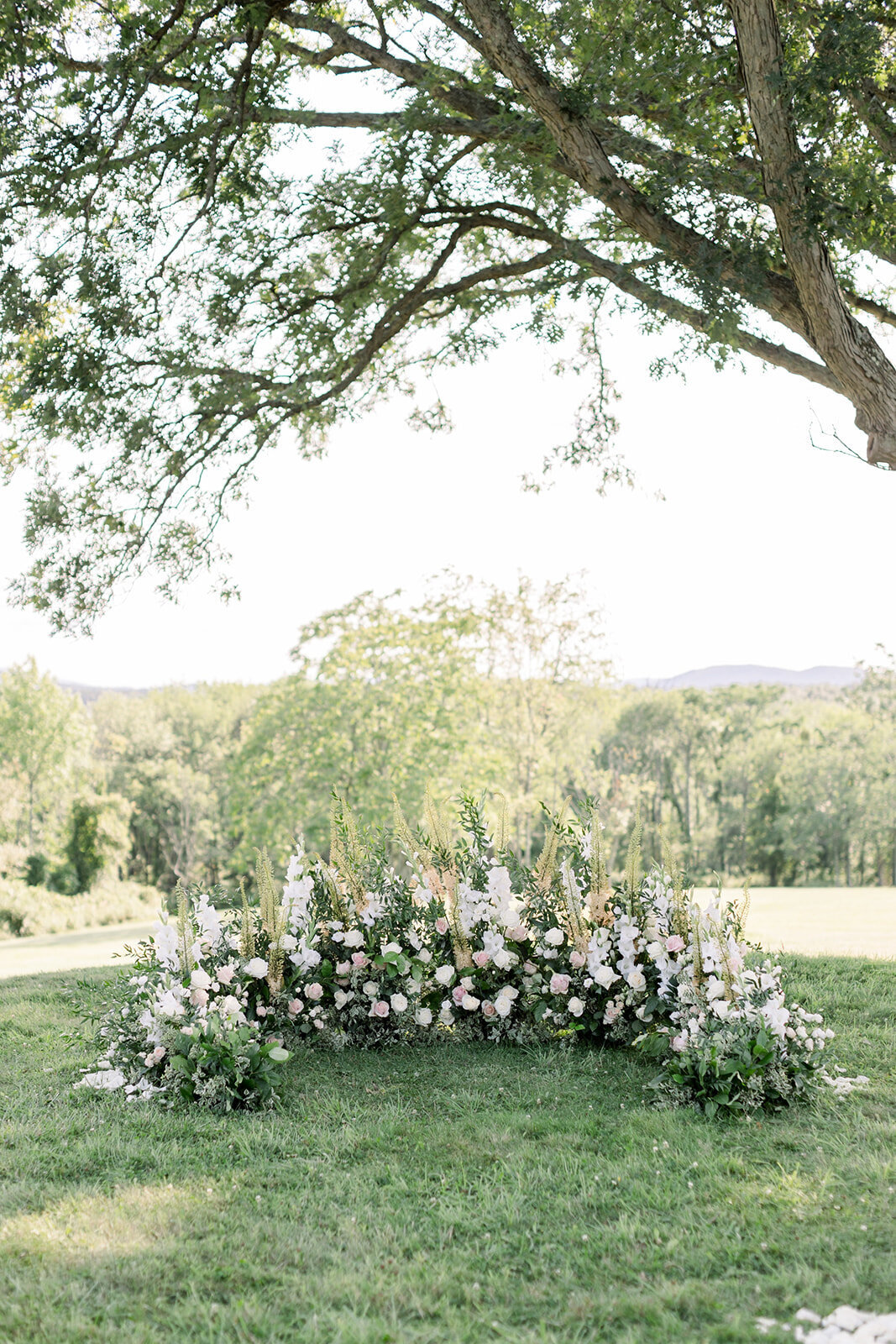 Details of a large curved floral arrangement for an outdoor wedding ceremony