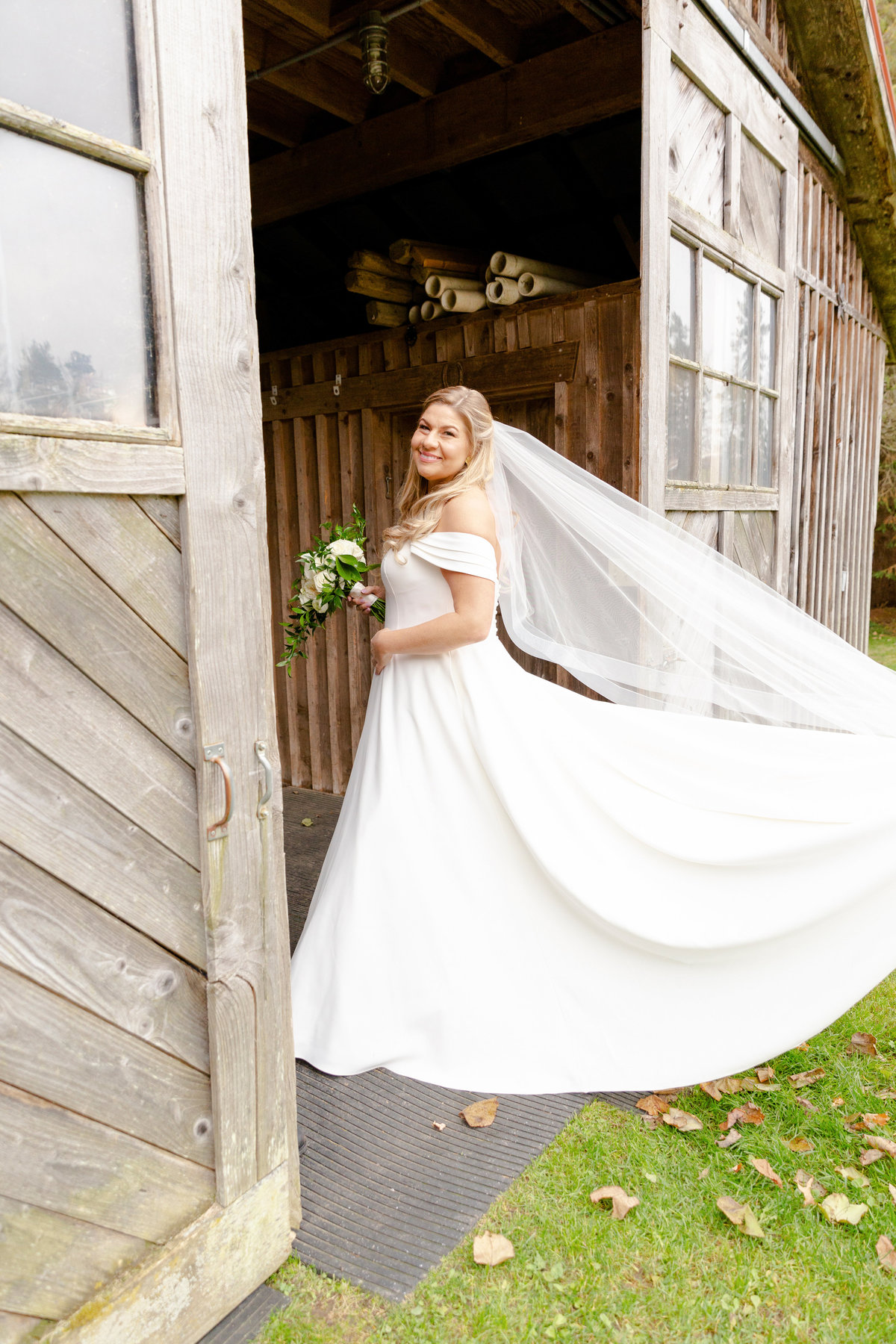 bride in wedding dress entering a barn