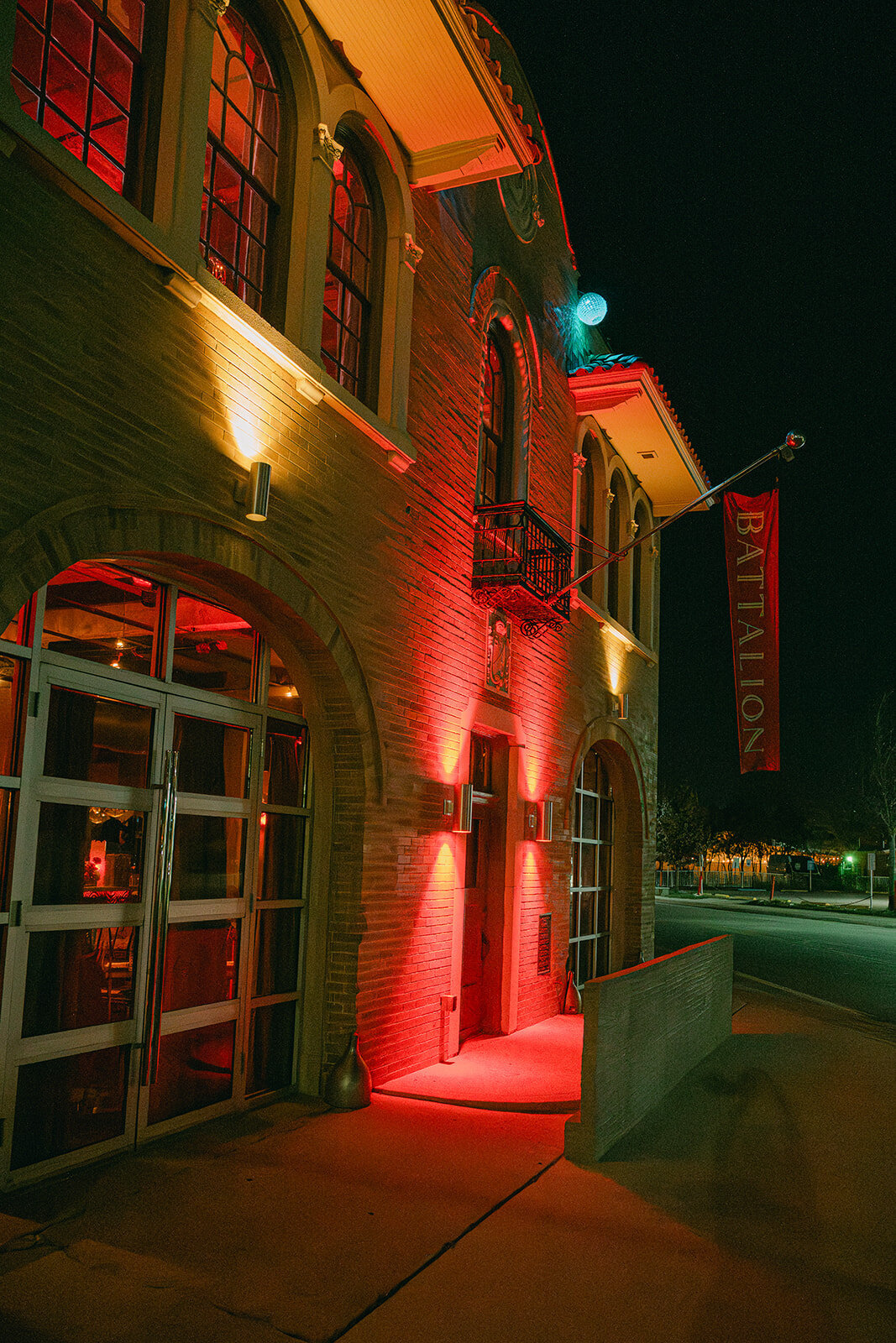 Dramatic night view of historic firehouse wedding venue glowing red in San Antonio, Texas