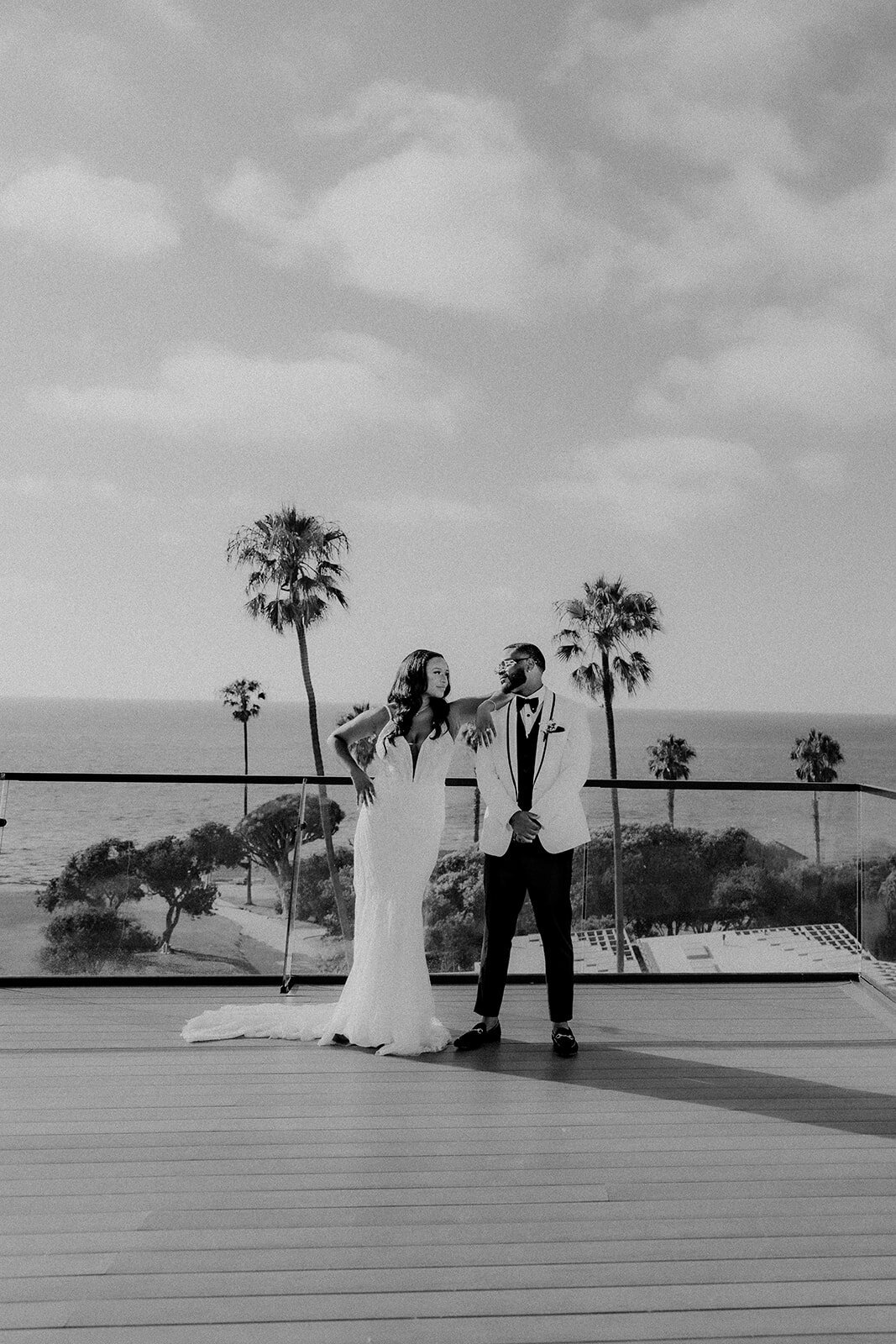 Bride and groom on balcony with the ocean and plam trees behind them in San Diego