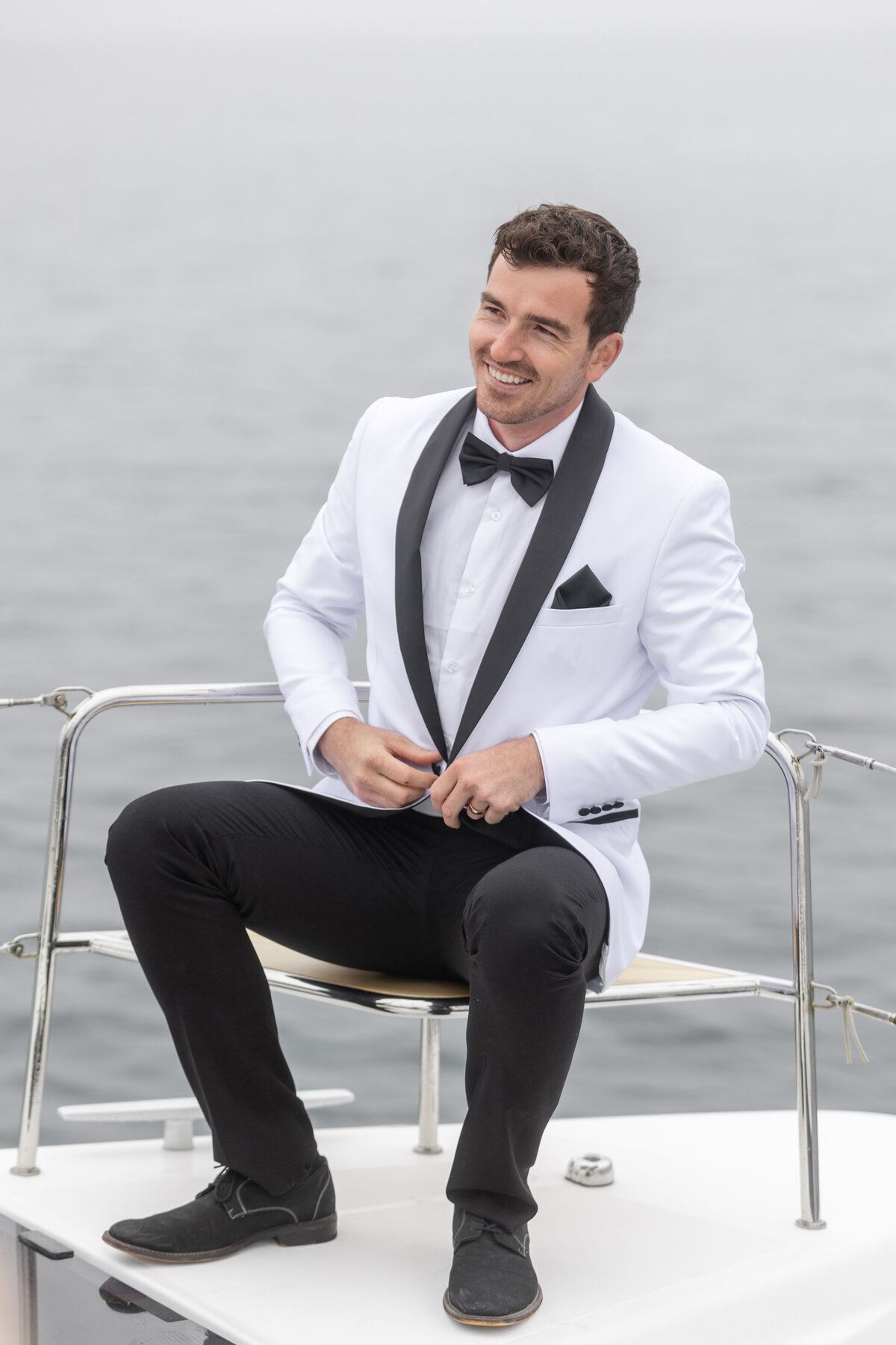Groom adjusting his suit coat while on catamaran