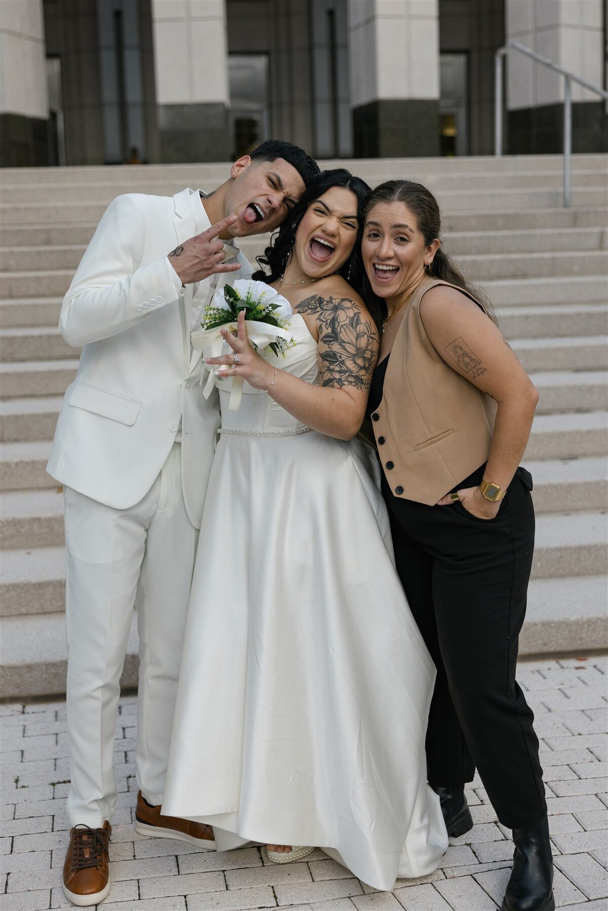 Female Destination Elopement Photographer celebrating with a joyful newlywed couple on the steps of Orange County Courthouse in Orlando, Florida.