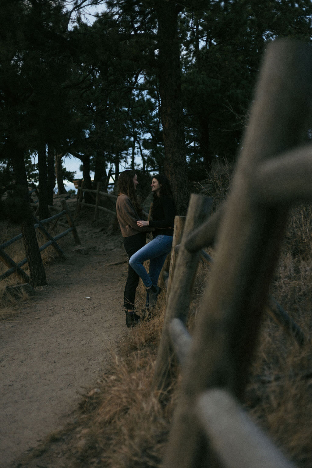 A couple leaning up against a wooden railing on a hiking path.