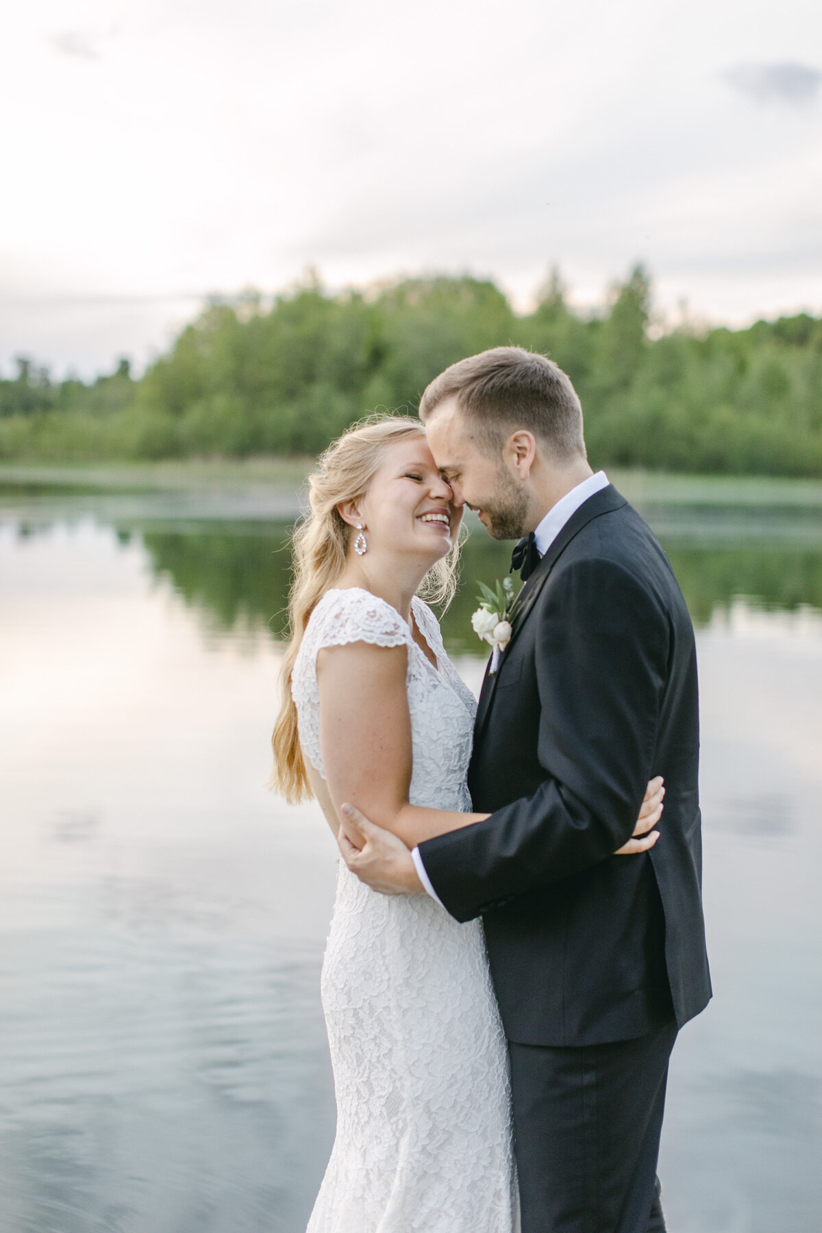 Bröllopspar skrattar vid vattnet vid Schenströmska