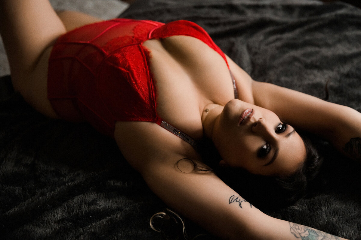 Dark moody lighting of woman in red body suit and brown hair