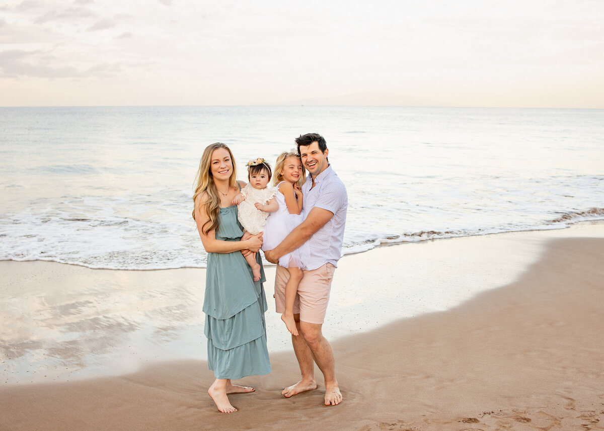 Maui Family Photographers capture parents holding children on beach during beach family photos