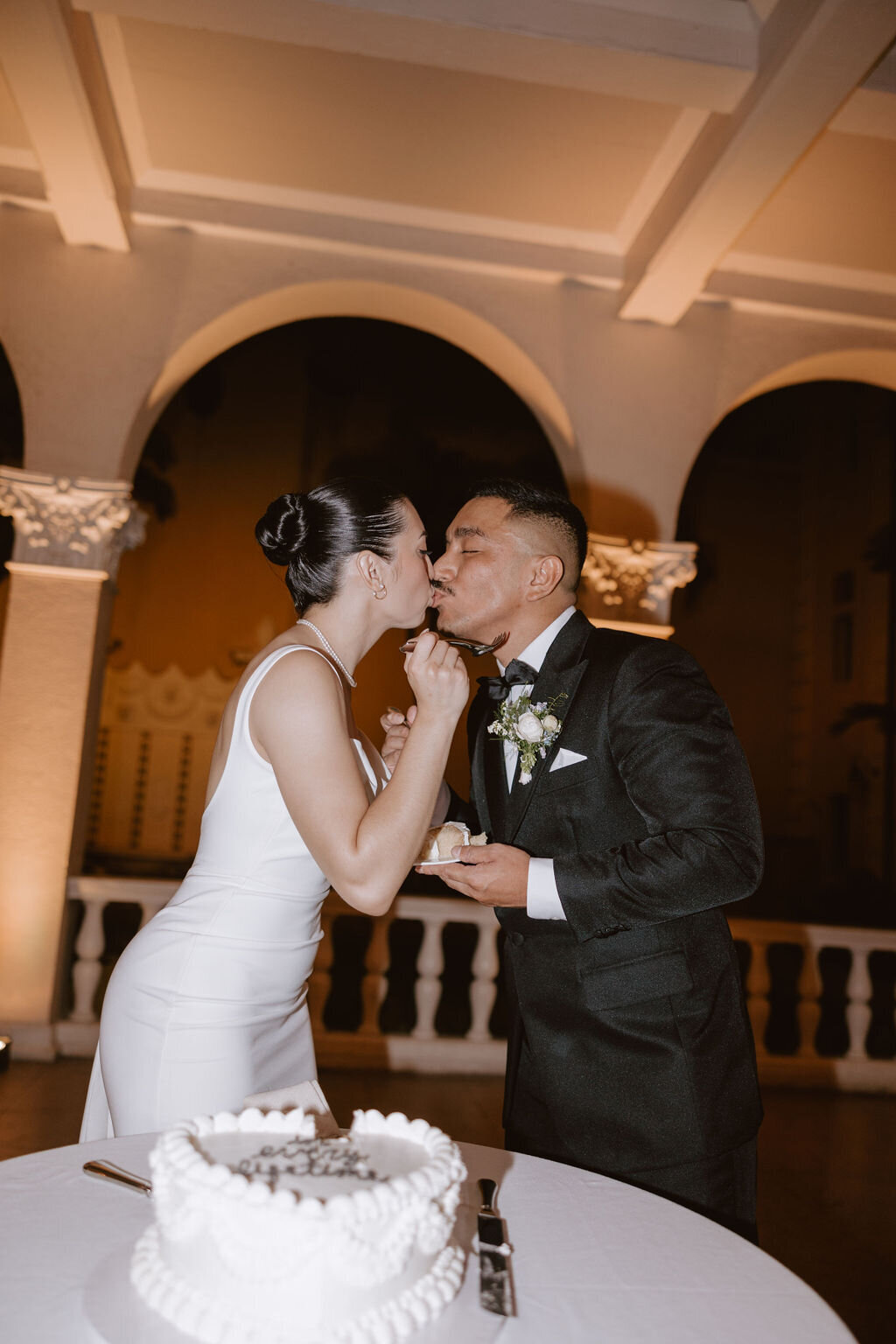 Bride and groom cake cutting kissing after feeding each other cake