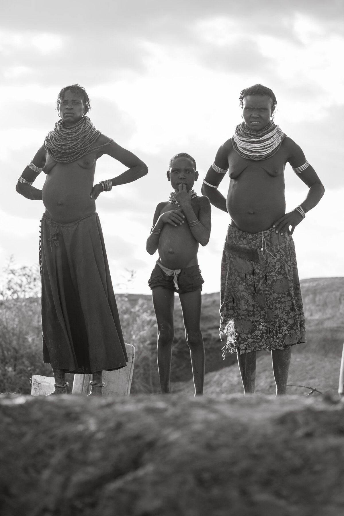 two mothers and a child on banks of omo river