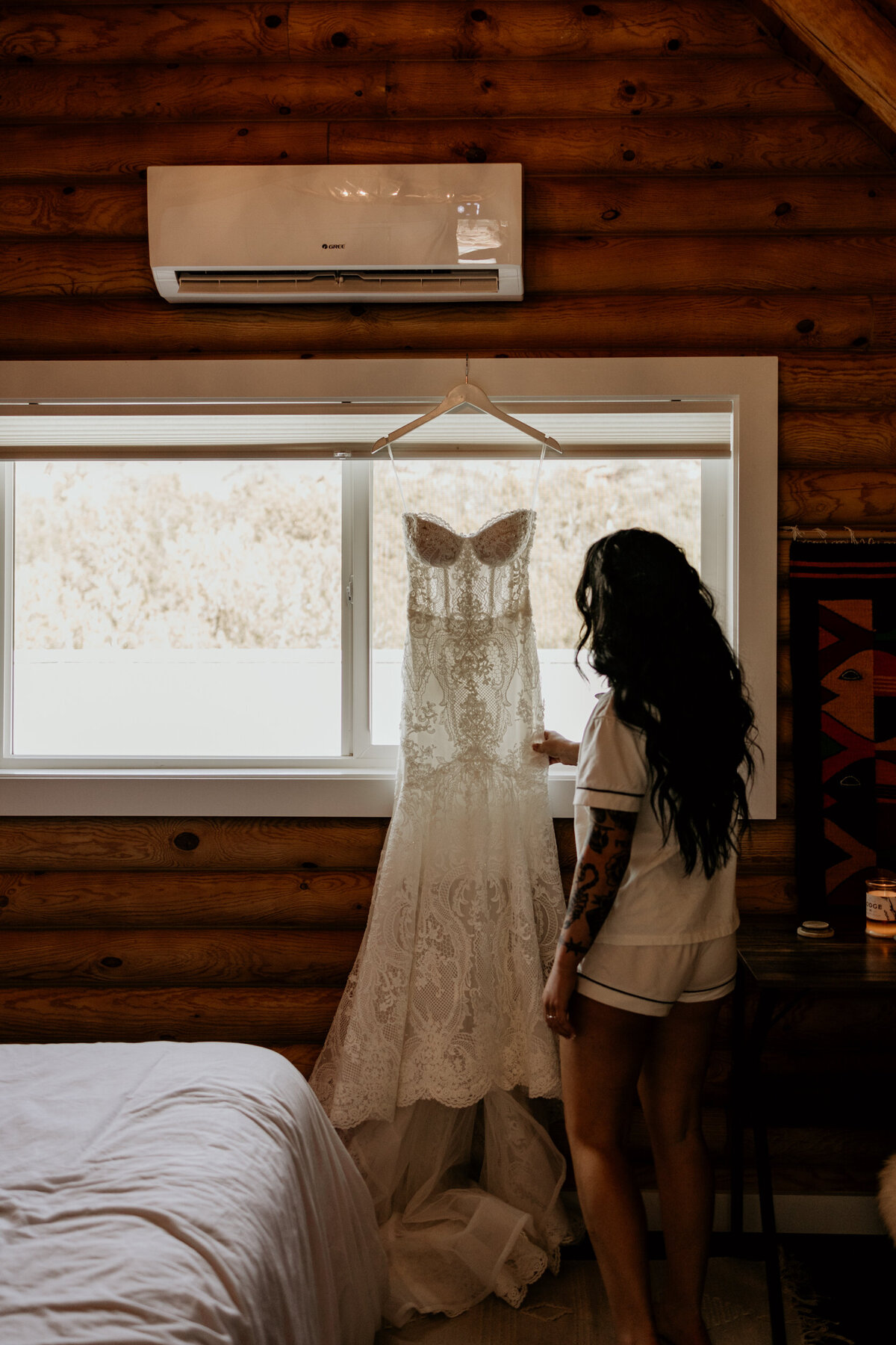bride looking at her wedding dress hanging in a window