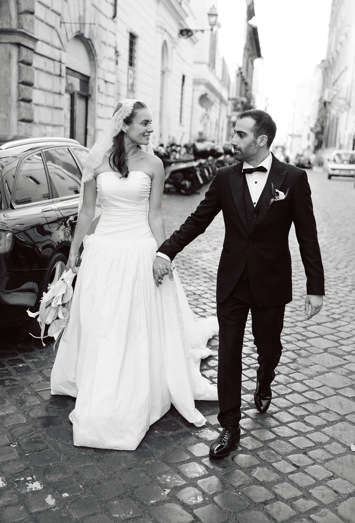Bride and groom walking together through historic street in black and white