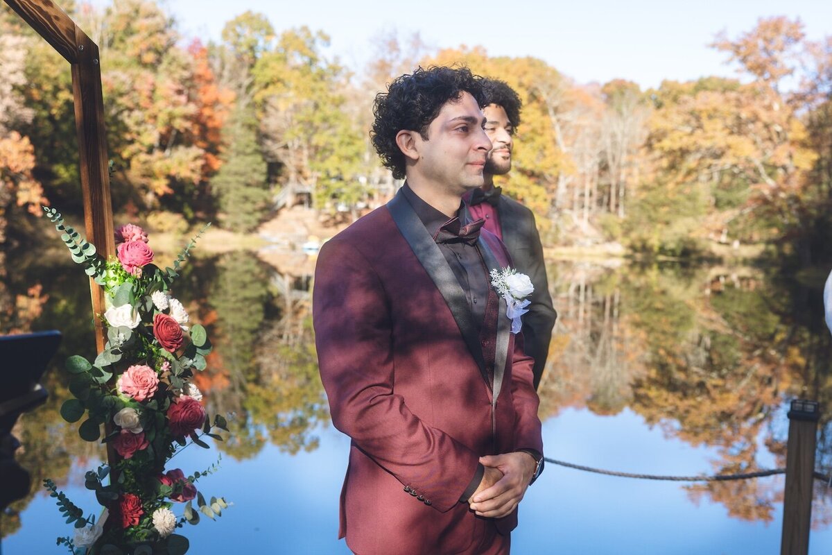 Groom waiting at the ceremony arch, smiling as he sees his bride.