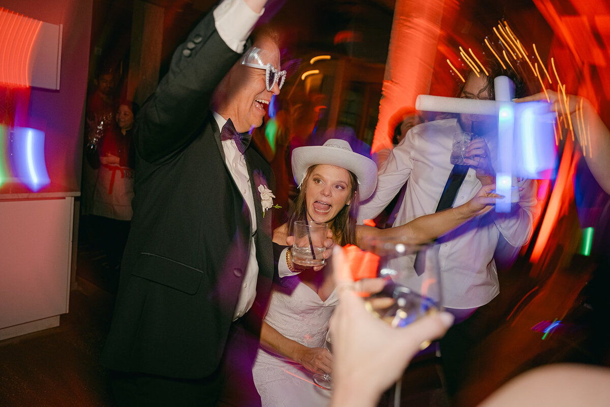 Modern reception moment with luxury bride and get father dancing under vibrant flash party lighting