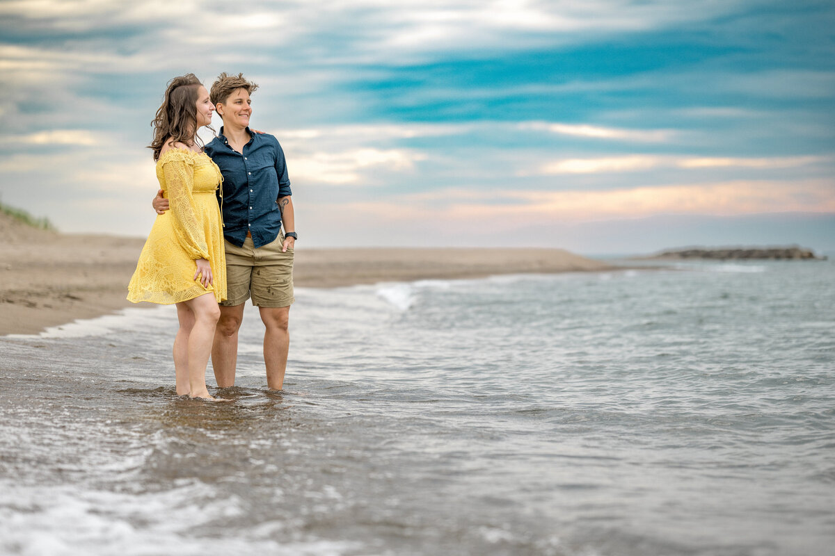 A couple standing at the water's edge with their arms around each other 