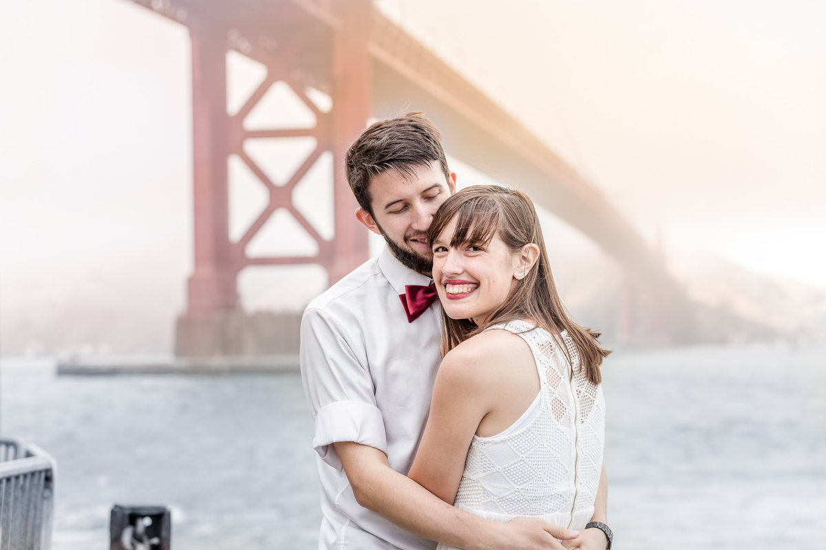 Husband and wife embrace in front of the San Francisco Bay Area Golden Gate Bridge