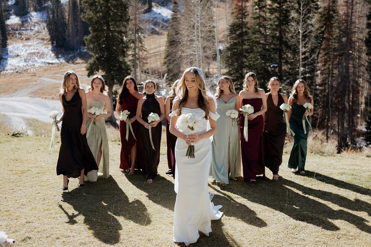 Bridal party walking and looking at each other while the bride walks in front with flowers. 