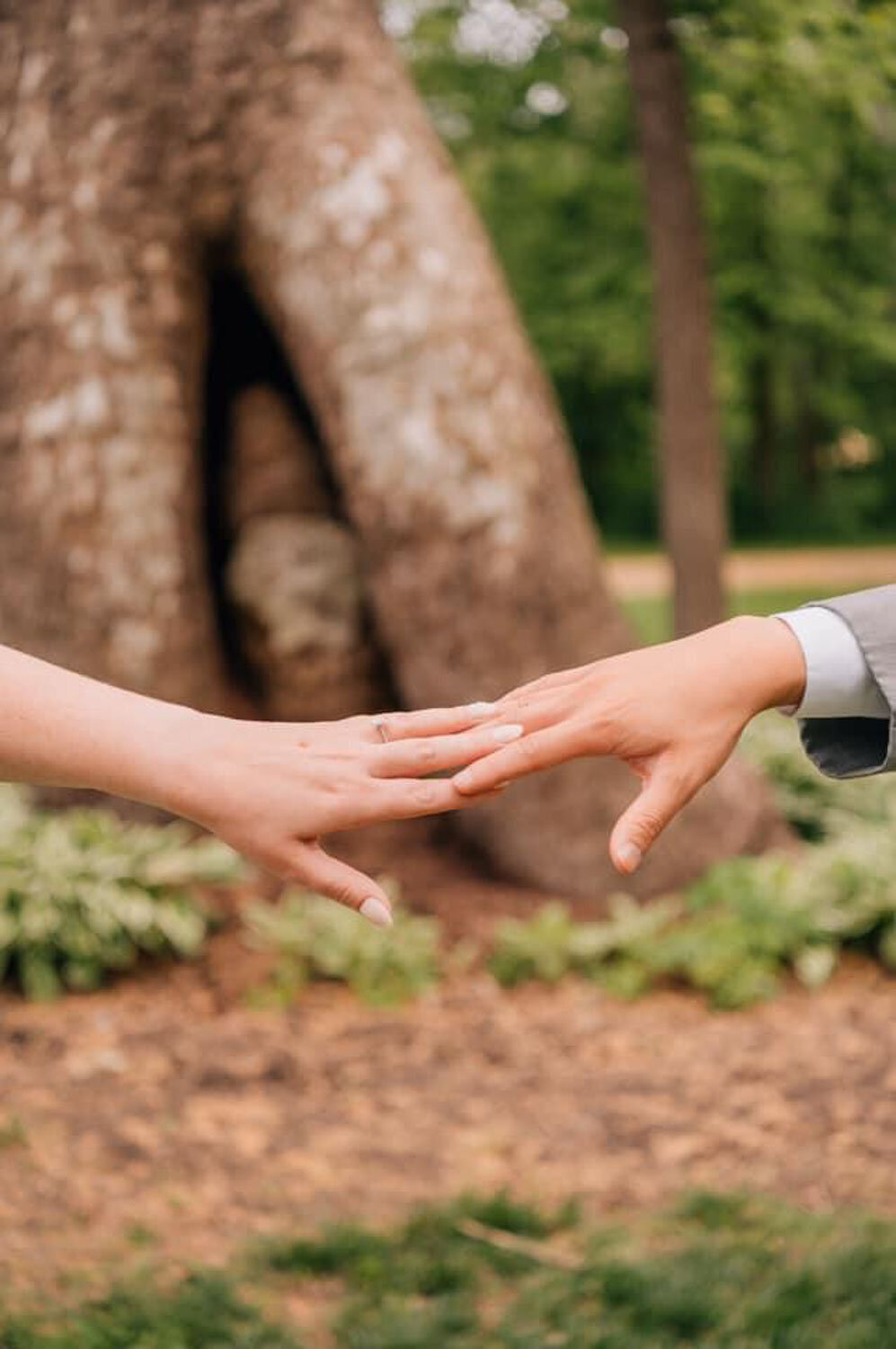 Close-up of bride and groom’s hands reaching toward each other