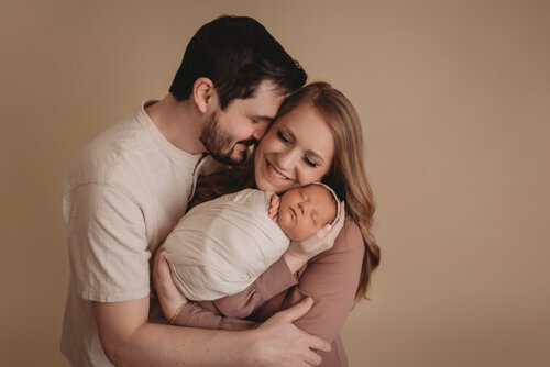 Baby girl sleeping for newborn portrait session with Atlanta Georgia newborn photographer snuggled up in a swaddle posing with her mom and dad