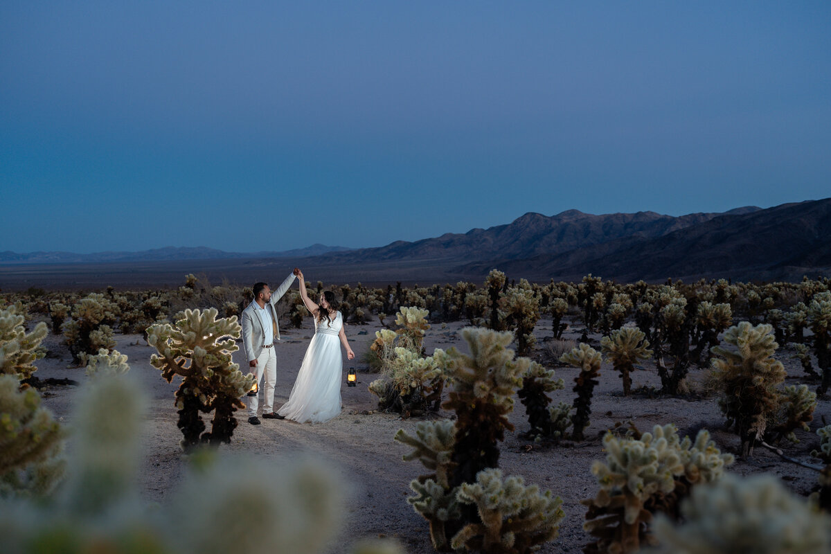 Joshua Tree elopement bride and groom at Cholla Cactus Garden during blue hour dancing with lanterns.