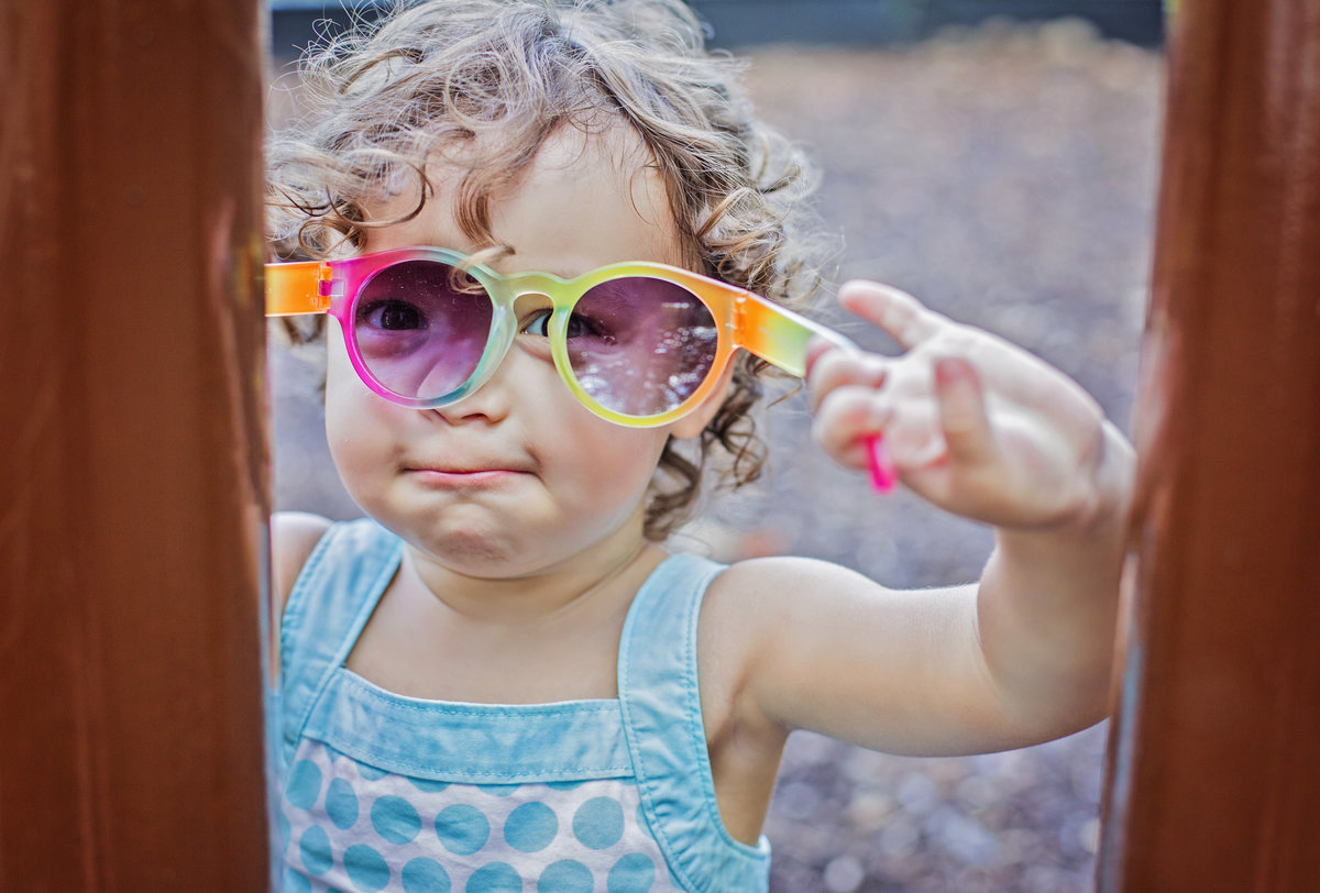 charlotte documentary photographer jamie lucido captures a candid image of a toddler at play with sunglasses