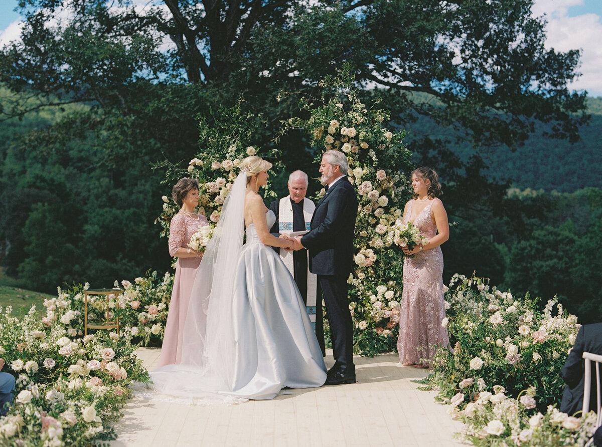 Epic ceremony backdrop for fall wedding at Blackberry Farms. Lush broken arch floral design for wedding ceremony backdrop. Garden inspired growing floral in colors of cream, white, blush, and green. Full coverage floral aisle for wedding ceremony. Floral meadows with petal heavy roses. Floral heavy flora design with elegant and whimsical design. Destination wedding at Blackberry Farm. Design by Rosemary & Finch Floral Design in Nashville, TN.