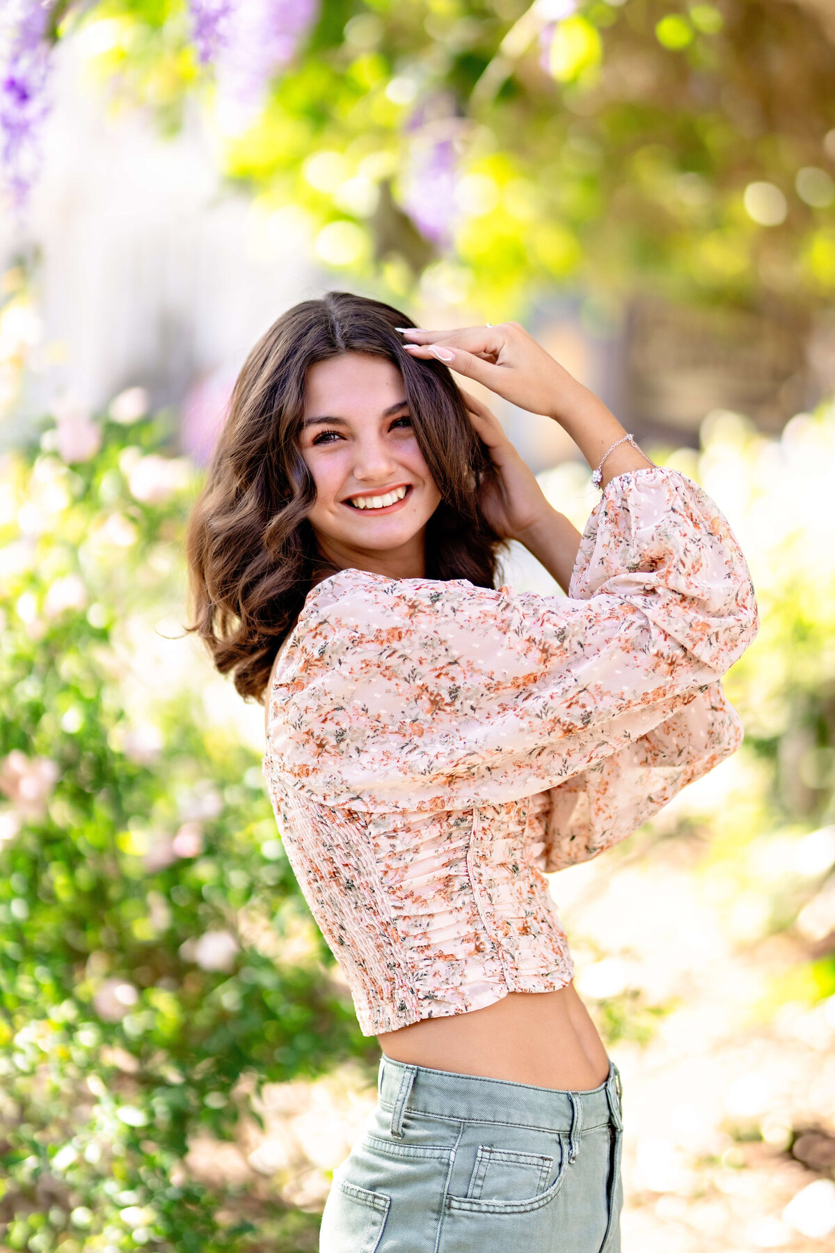 Teen girl smiling with flowers in foreground during vibrant Windermere session