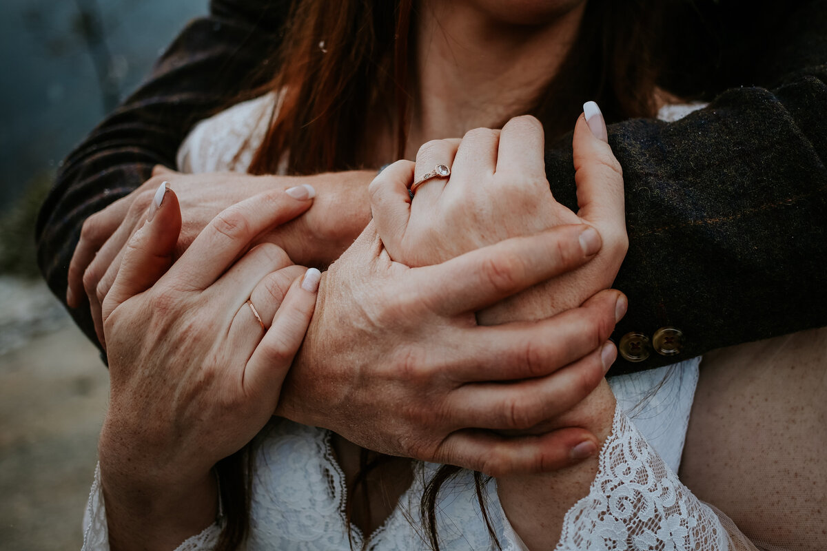 Close up shot of bride and grooms hands intertwined.