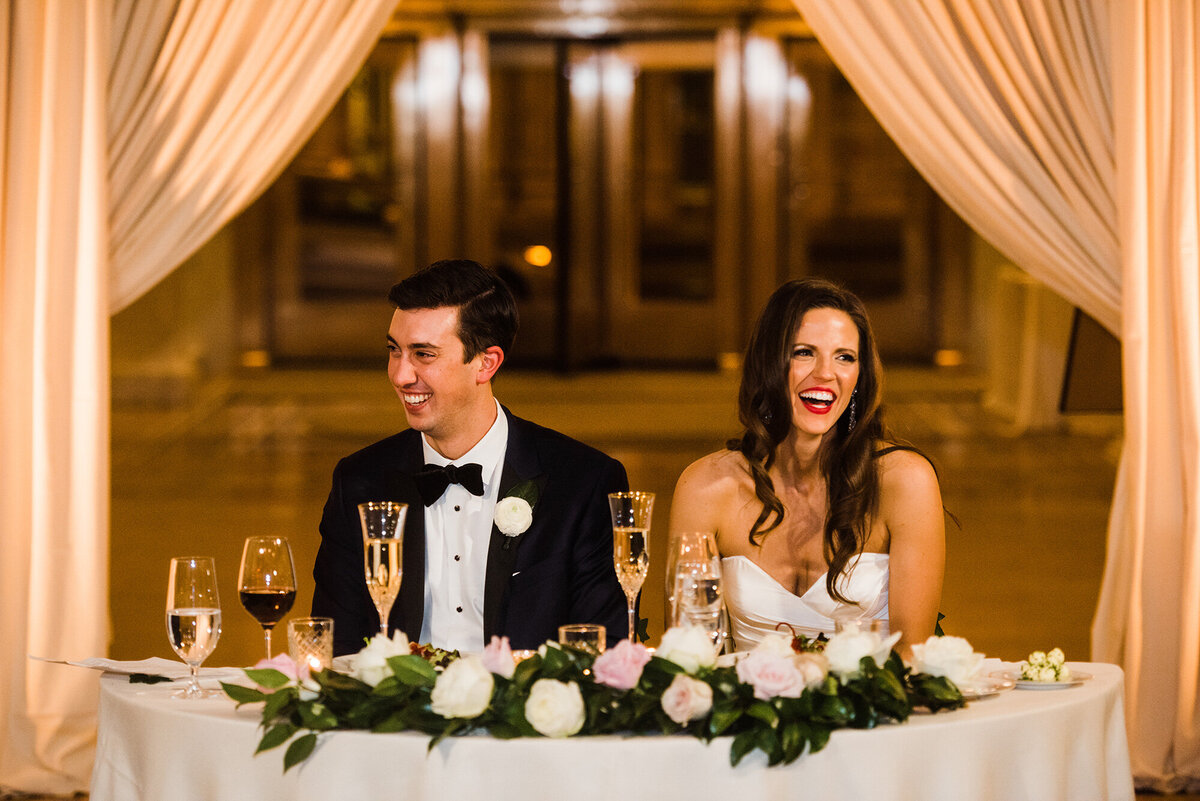 Bride and groom laugh as they listen to their wedding toasts while at the Rookery in Chicago.