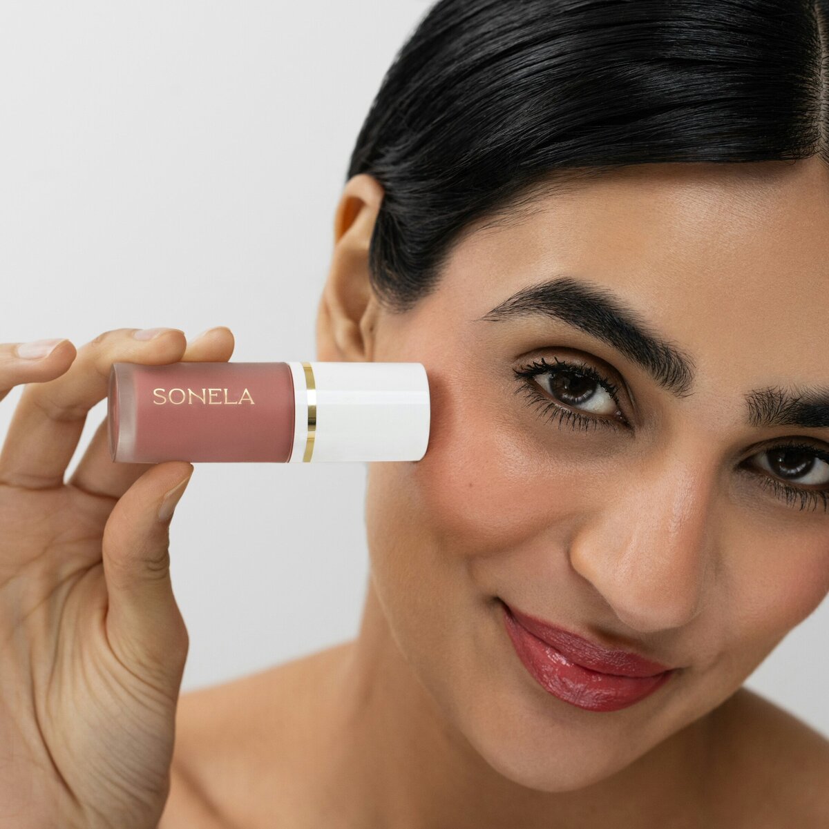 Model holding cosmetics product with Sonela Beauty’s gold brand logo, designed by Sarah Shuttle