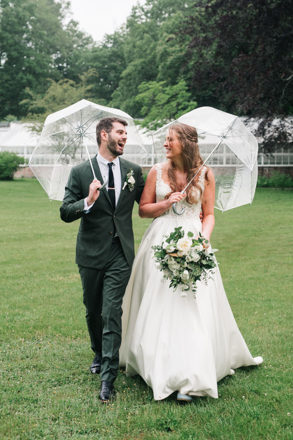 Bride and groom facing each other both are holding a clear umbrella